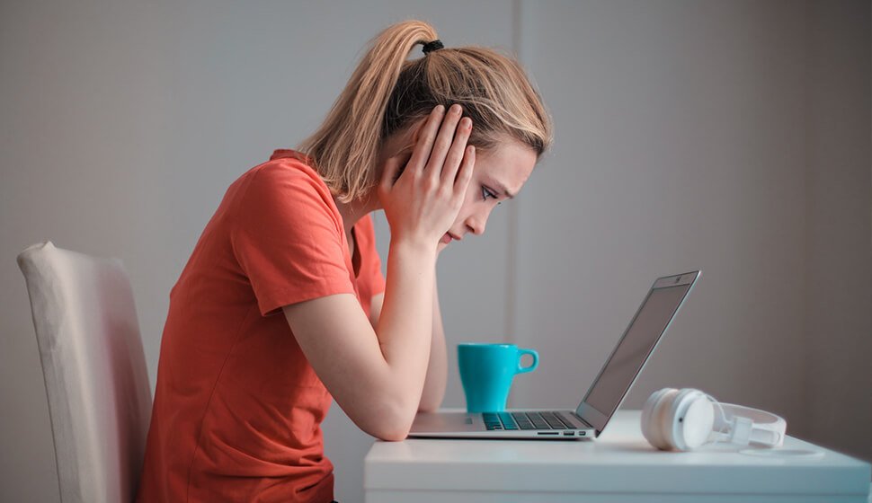 Student looking stressed while studying at a laptop